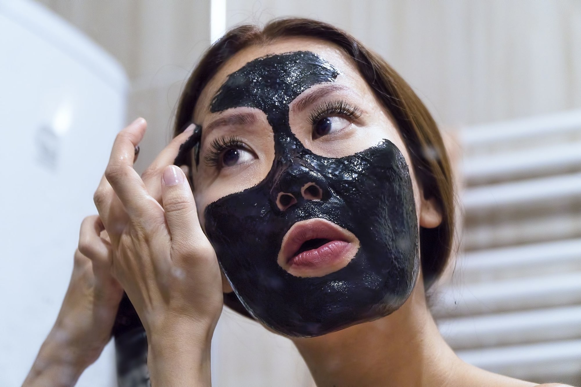 Женщина наносит маску на лицо